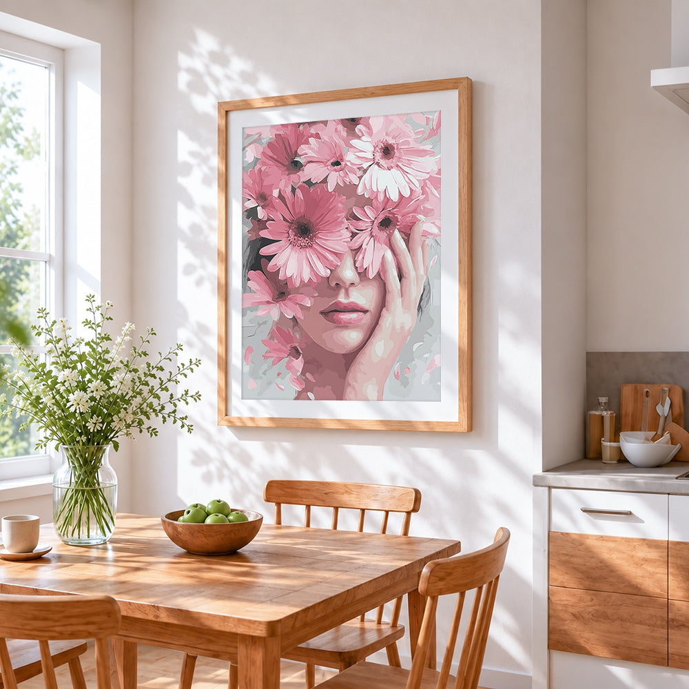 Woman holding pink gerbera daisies cross stitch artwork displayed on wall as home decor