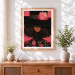 Finished woman in black hat with pink flower cross stitch artwork displayed