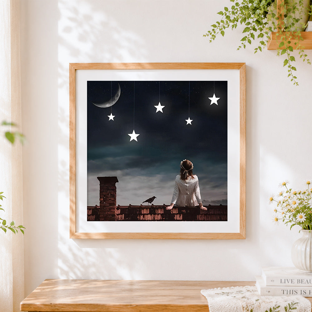Finished woman on rooftop with hanging stars cross stitch artwork displayed