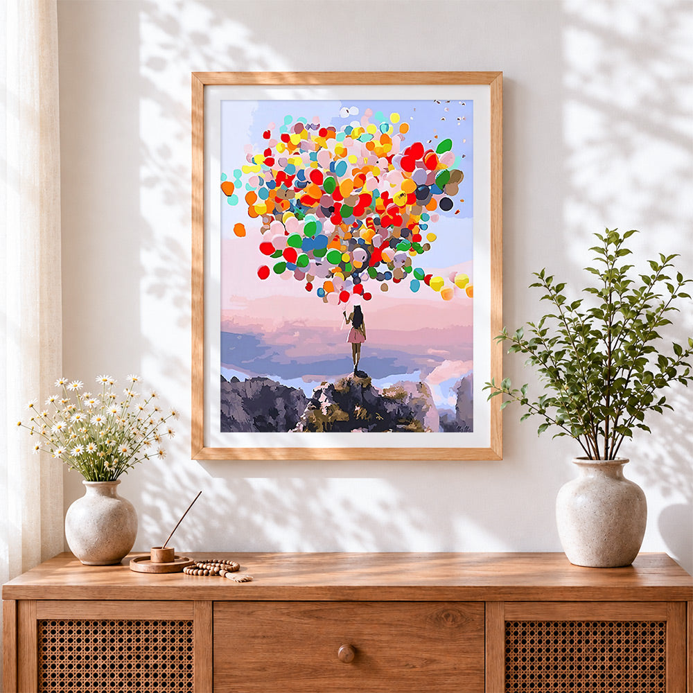 Finished woman with colourful balloons on a mountain cross stitch artwork displayed