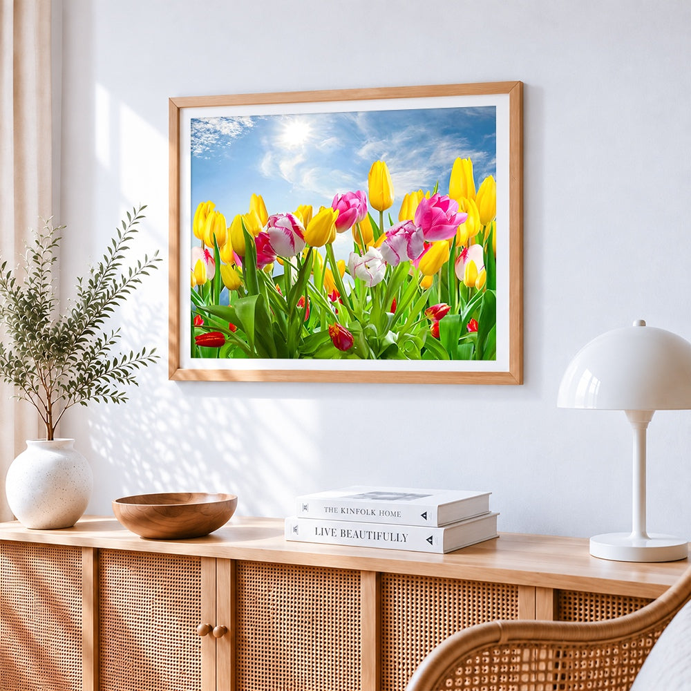 Yellow and pink tulips under blue sky cross stitch artwork displayed on wall as home decor