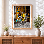Finished yellow bicycle in the city cross stitch artwork displayed