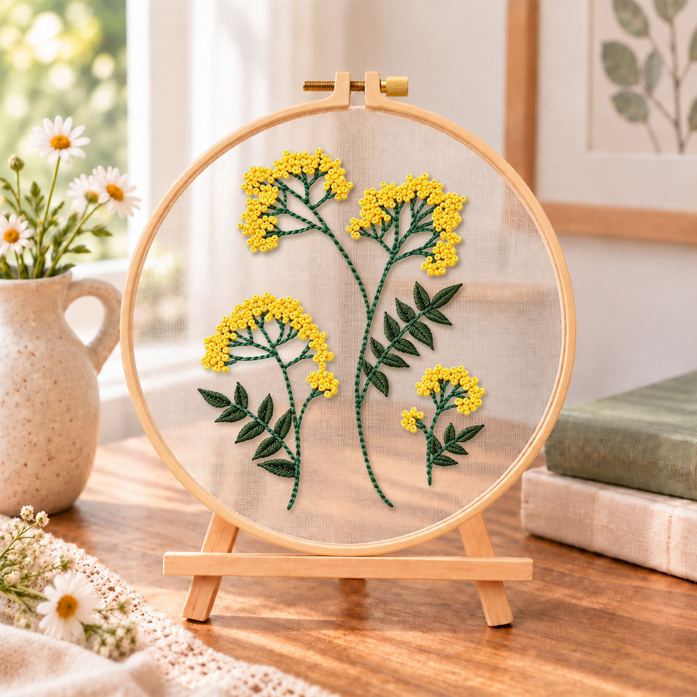 Yellow wildflower bouquet embroidery kit finished hoop displayed on a wooden stand as cozy tabletop decor
